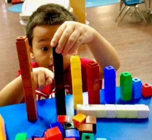 A preschooler playing with blocks to build stepping stairs.