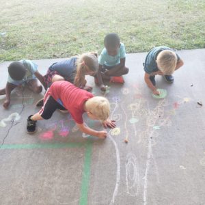 Children at daycare playing with chalk.